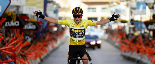 Jonas Vingegaard entra a meta en una etapa de Itzulia 2023 con los brazos en alto, celebrando su victoria. Viste el maillot amarillo de líder de la Itzulia diseñado y confeccionado por Gobik.  